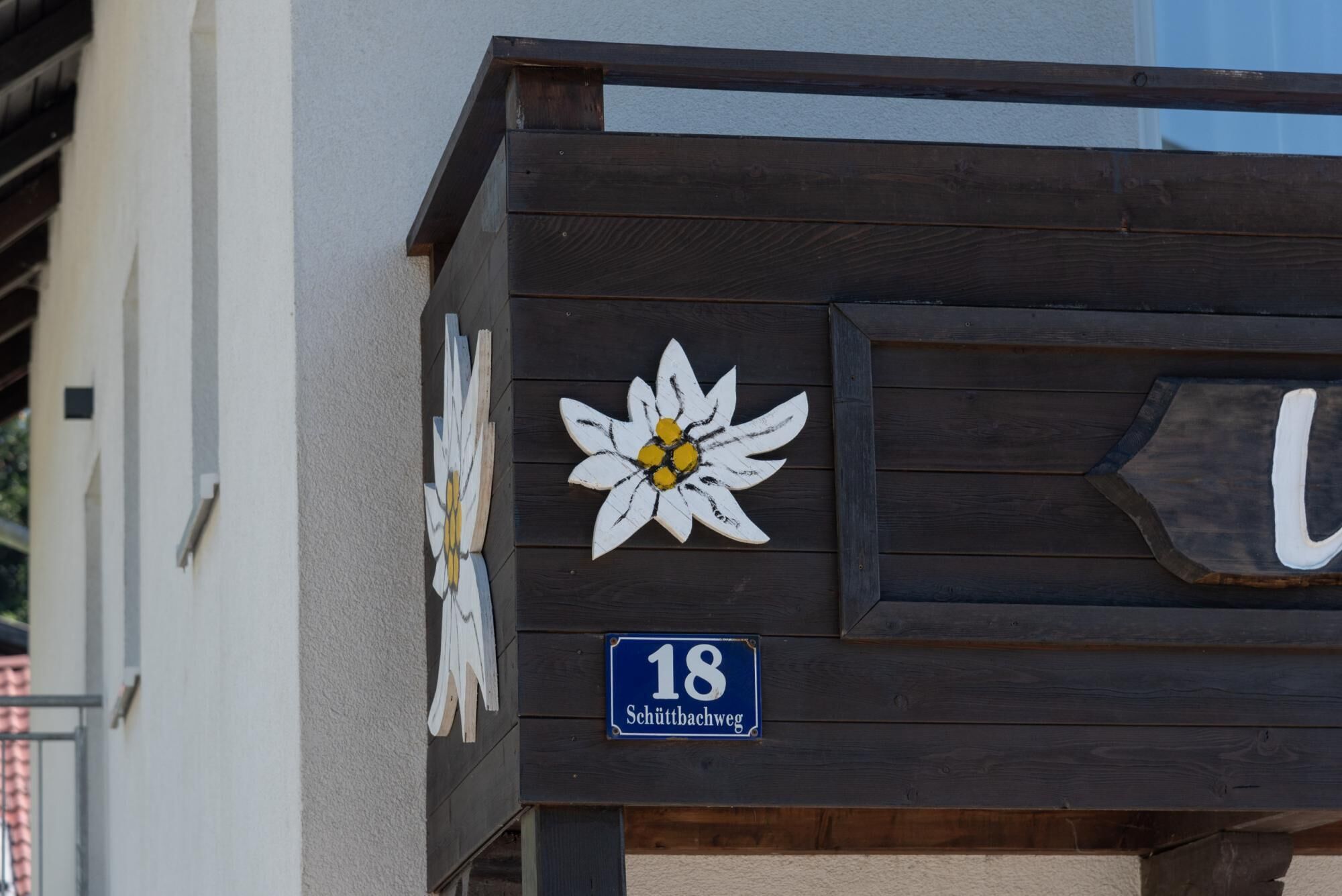 Une structure en bois ornée de motifs floraux et portant une plaque avec le numéro de la maison.