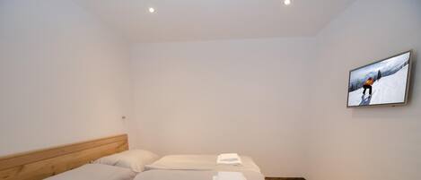 A single bed with a wooden headboard, white bedding, and a folded towel on the footboard.