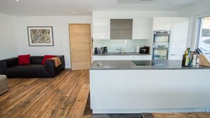 A modern kitchen with white cabinets, a built-in oven, and a coffee machine. - Superb Alpine Lodges Zell am See 4pax (Zell am See)