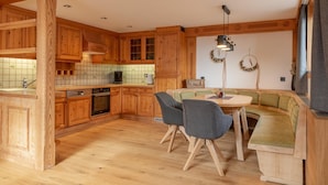 Una cocina con armarios de madera, una zona de comedor con un banco y un horno empotrado.