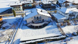 A residential area with multiple houses, some with snow-covered roofs, surrounded by snow-covered ground. - Panorama Apartments Bruck TOP 1 (Bruck an der Grossglocknerstrasse)