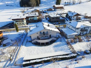 A residential area with multiple houses, some with snow-covered roofs, surrounded by snow-covered ground. - Panorama Apartments Bruck TOP 1 (Bruck an der Grossglocknerstrasse)