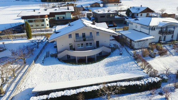 A residential area with multiple houses, some with balconies, surrounded by snow-covered ground. - Panorama Apartments Bruck TOP 1 (Bruck an der Grossglocknerstrasse)