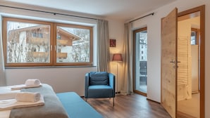 Ein modernes Hotelzimmer mit großem Fenster, einem blauen Sofa, einer Holztür und einer Lampe.