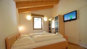 A bedroom with a wooden bed, a television on the wall, and a window with a view of the outdoors. - Ski Chalet Jim 300 m From ski Lift (Zell am See)