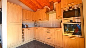 A kitchen with wooden cabinets, a Bosch oven, and a stainless steel sink. - Ski Chalet Jim 300 m From ski Lift (Zell am See)