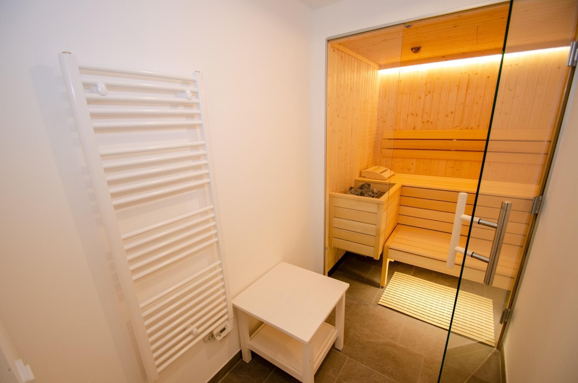 A small, compact room with a wooden wardrobe, a white radiator, and a small table.