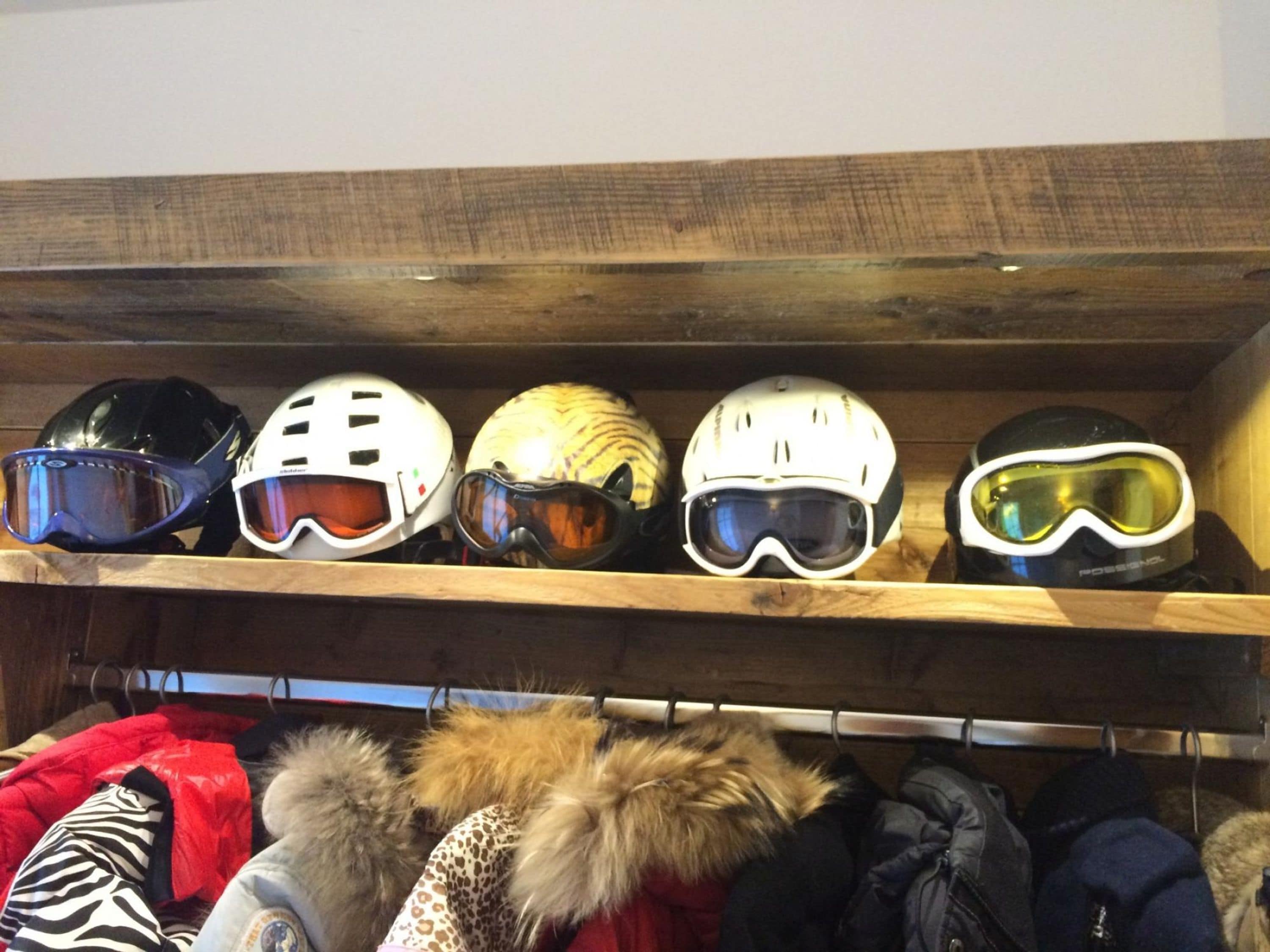 Un perchero con cascos y un estante con chaquetas de invierno.