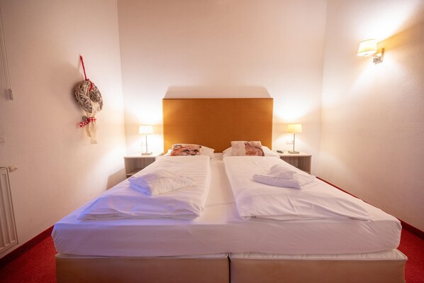 A double bed with white linens, two bedside tables with lamps, and a wall-mounted light fixture. - Finest Penthouse All Seasons Lodge Kaprun (Kaprun)