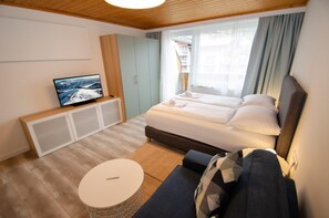 Une chambre d’hôtel moderne avec un grand lit, un téléviseur posé sur un meuble, une petite table ronde et un canapé.