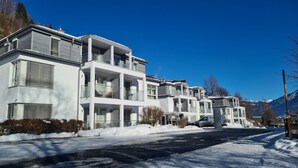 A modern residential building with multiple balconies, a garage, and a snow-covered driveway. - Apartment Glacier View 12 1 With Balcony (Kaprun)