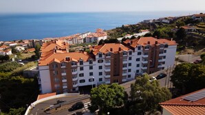 A multi-story hotel with a red-tiled roof, located near a coastal area with a view of the sea. - Savana Apartment by Atlantic Holiday (Santa Cruz)