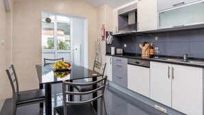 A modern kitchen with a dining table, chairs, and a window. - Savana Apartment by Atlantic Holiday (Santa Cruz)