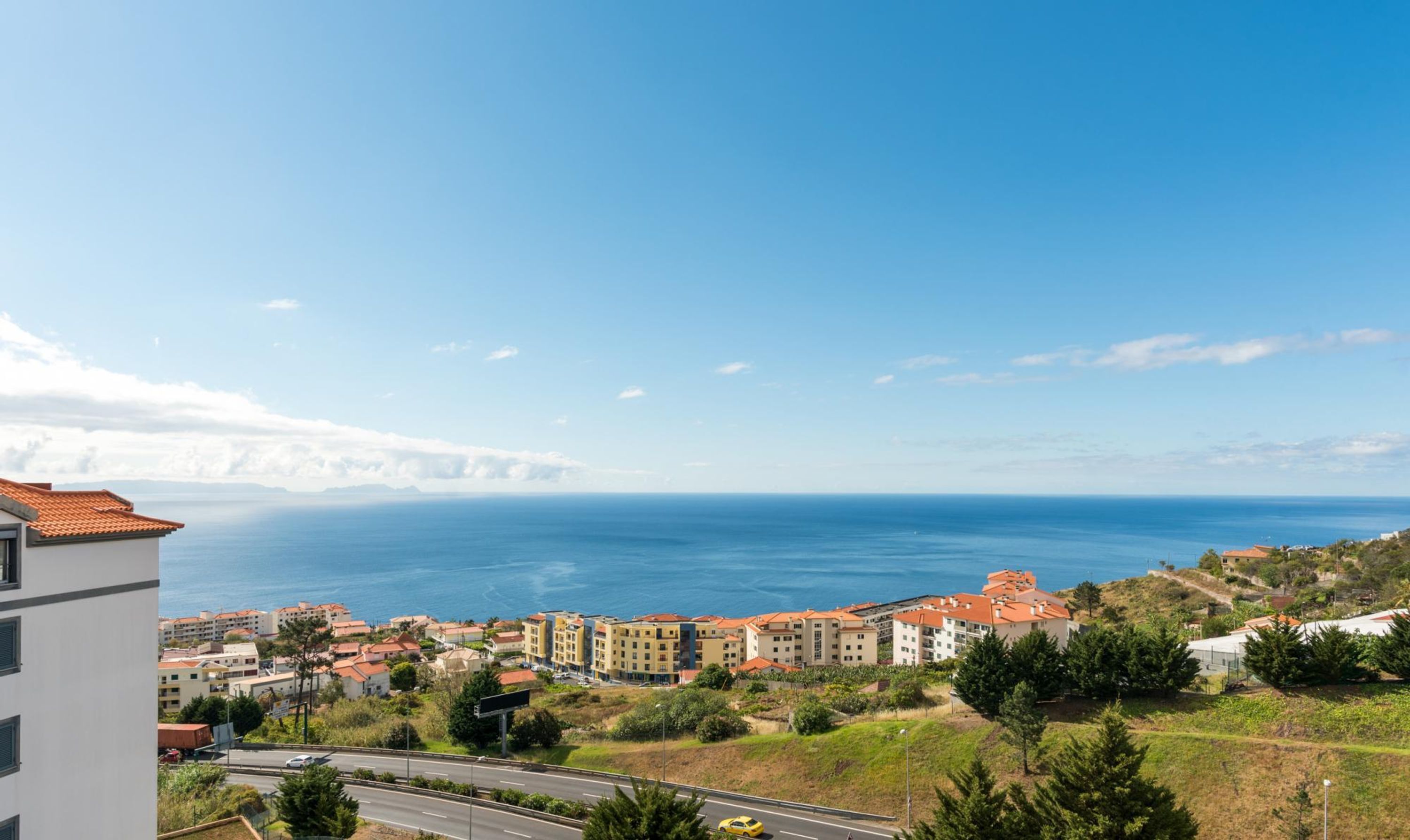 Uma vila costeira com edifícios, uma estrada e vista para o mar.