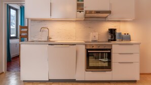 A modern kitchen with white cabinetry, a stainless steel oven, and a built-in dishwasher.