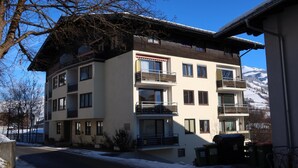 A multi-story hotel with balconies, a snow-covered ground, and a mountain in the background.