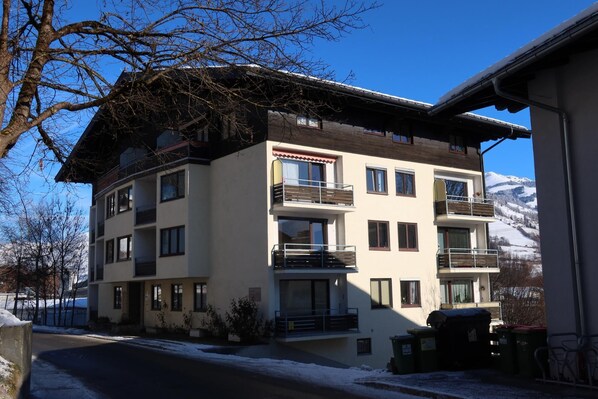 A multi-story hotel with balconies, a snow-covered ground, and a mountain in the background.