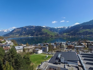 Une ville au bord d’un lac, avec des bâtiments, un parking et des montagnes en arrière-plan.