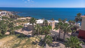 A coastal property with a patio, palm trees, and a view of the sea.