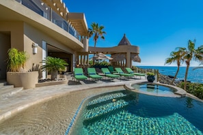 A resort with a pool, lounge chairs, and a view of the ocean.