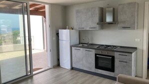 Une cuisine moderne avec une porte-fenêtre coulissante donnant sur un balcon.