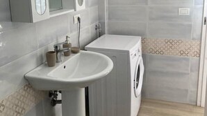 Une salle de bain avec un lavabo, un miroir et un lave-linge.
