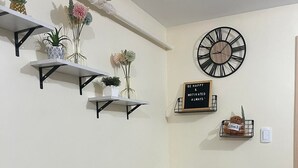 Een eetruimte met een glazen tafel, stoelen en een klok aan de muur.