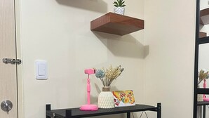 Een kamer met een zwarte metalen schapunit, een roze lamp en een kleine plant in pot.