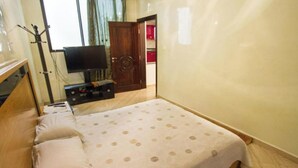 Une chambre à coucher avec un lit, des oreillers, une télévision et une armoire en bois.