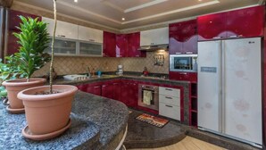 Une cuisine avec des meubles de couleur rouge, un réfrigérateur blanc et un plan de travail en granit.
