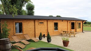 Eine Holzhütte mit Whirlpool, Liegestühlen und einem Picknicktisch.