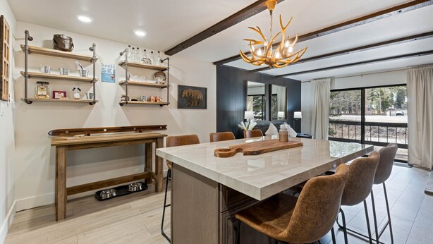 A modern kitchen with a central island, wooden shelves, and a chandelier. - Luxurious 2 Bedroom Base Camp Condo - Steps from Kirkwood Village 2 Condo by RedAwning (Kirkwood)