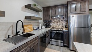 A modern kitchen with stainless steel appliances, wooden cabinets, and a marble backsplash. - Luxurious 2 Bedroom Base Camp Condo - Steps from Kirkwood Village 2 Condo by RedAwning (Kirkwood)