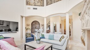 A spacious living area with a high ceiling, a large arched doorway, and a fireplace. - Luxury Home Villa D' Amore Southern Florida Paradise Sleeps 10 5 Bedroom Villa by RedAwning (Fort Lauderdale)