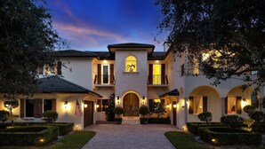 A two-story house with a central entrance, arched doorways, and a balcony on the upper floor. - Luxury Home Villa D' Amore Southern Florida Paradise Sleeps 10 5 Bedroom Villa by RedAwning (Fort Lauderdale)
