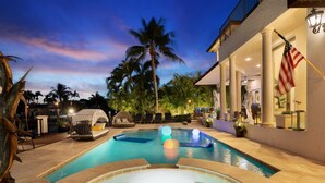 A swimming pool with a hot tub, lounge chairs, and a statue. - Luxury Home Villa D' Amore Southern Florida Paradise Sleeps 10 5 Bedroom Villa by RedAwning (Fort Lauderdale)