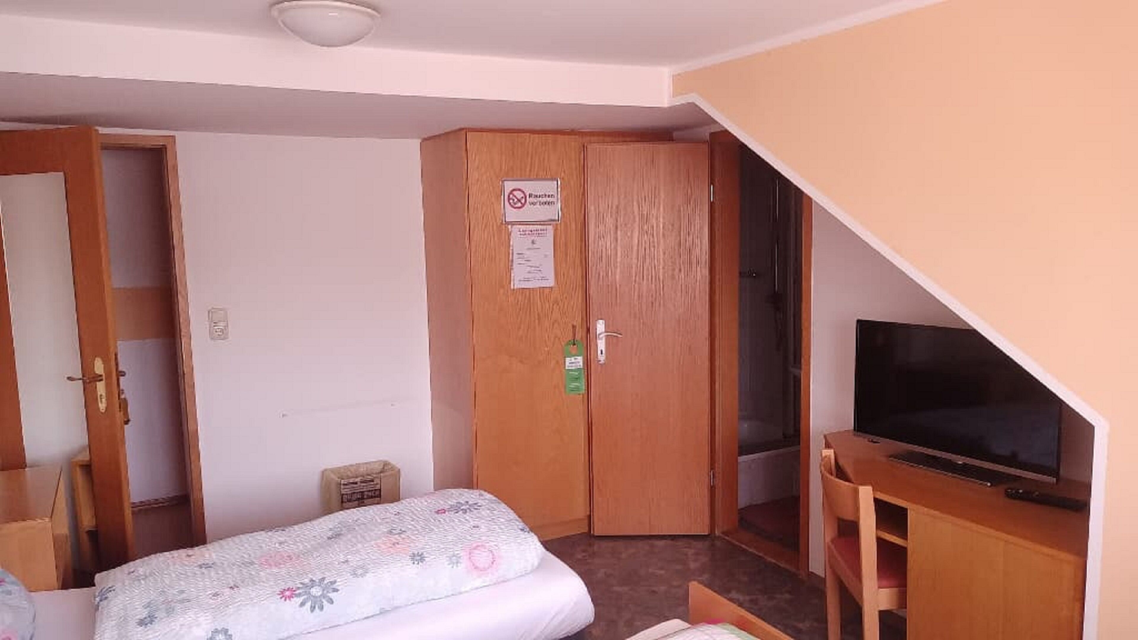 Un dormitorio con cama, televisor y armario.