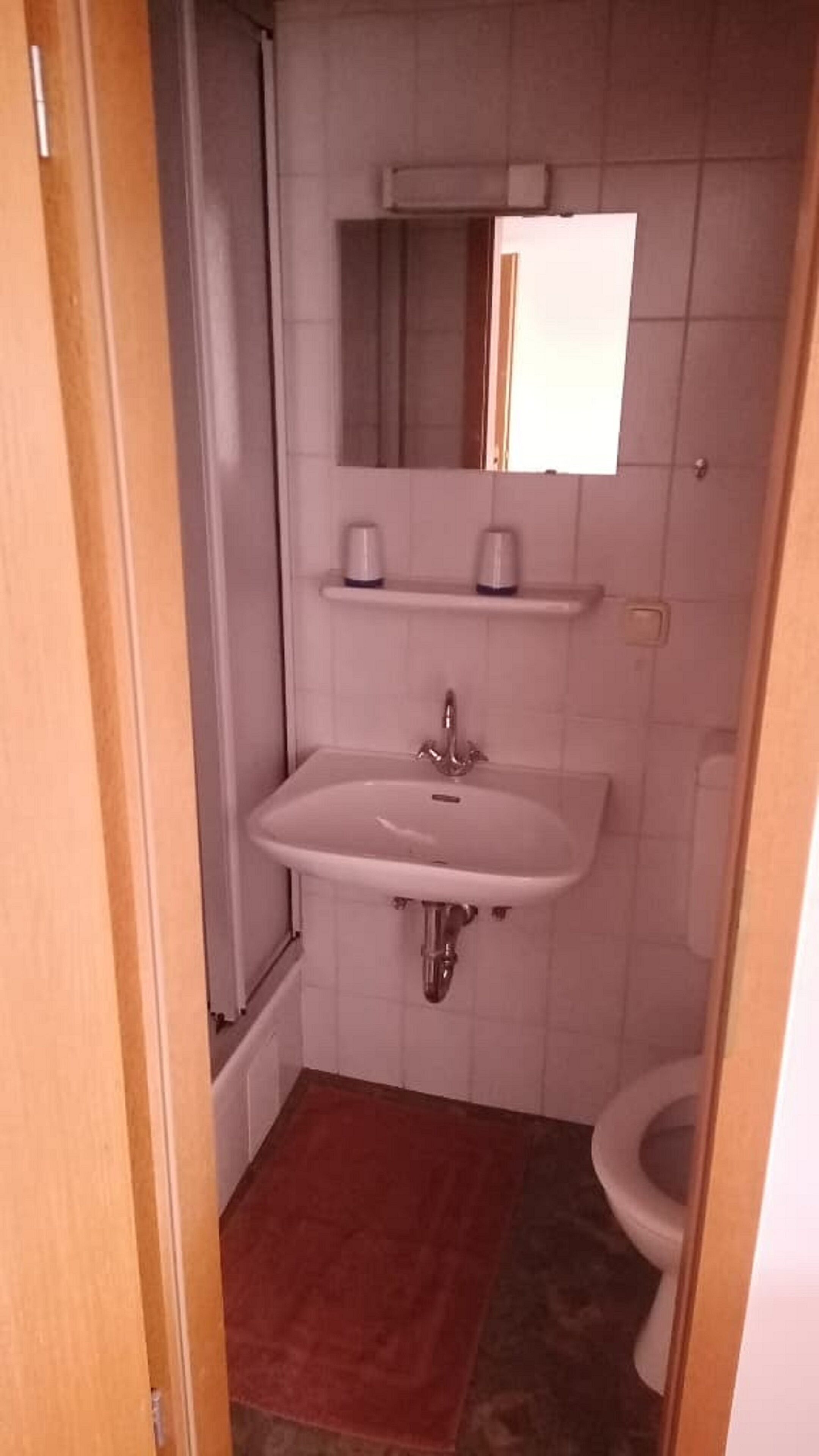 Een kleine badkamer met een wit wastafel, een spiegel erboven en een toilet.