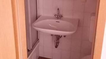 Een kleine badkamer met een wit wastafel, een spiegel erboven en een toilet.