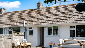 A white cottage with a tiled roof, a wooden deck, and a small garden area. - Suncroft (Port Isaac)