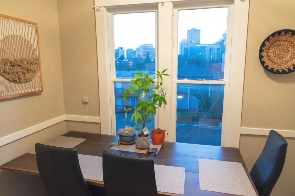 Una sala conferenze con vista sulla città, un vaso con una pianta e un pannello decorativo tessuto.