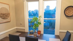 A conference room with a city view, a potted plant, and a woven wall hanging.