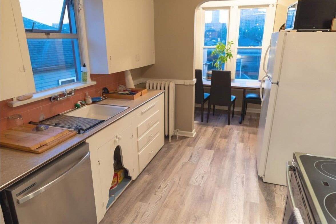 Cucina con piano cottura, lavello e pensili, zona pranzo con tavolo e sedie, e vista esterna.