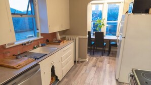 A kitchen with a stove, sink, and cabinets, a dining area with a table and chairs, and a view of the outside.
