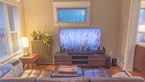 A living room with a flat-screen TV, leather sofas, a small table with a tray, and a radiator.