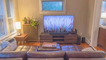 A living room with a flat-screen TV, leather sofas, a small table with a tray, and a radiator.
