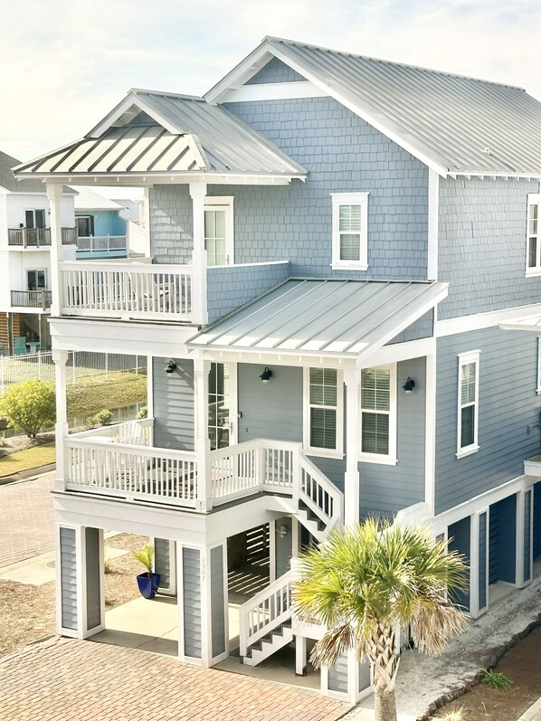 A two-story house with a balcony, a covered porch, and a small garden area.