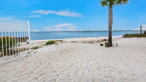 Platja sorrenca amb una palmera i una tanca blanca.