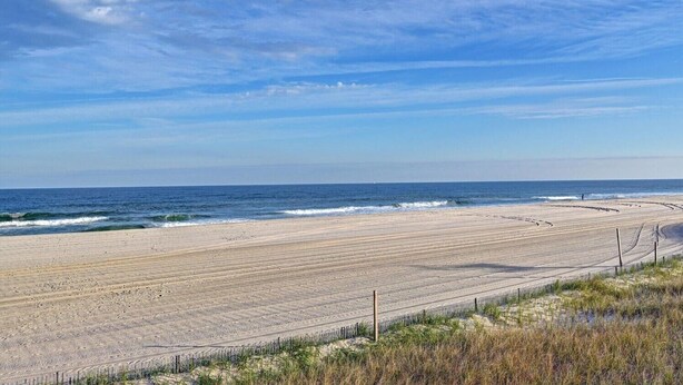 A wide beach with gentle waves, a clear sky, and a distant horizon. - Beach Block Retreat w/Patio, Off Street Parking, Linens & Towels, Beach Gear (Seaside Heights)