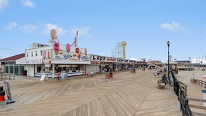 A boardwalk with various shops and restaurants, including signs for 'Aoh's' and 'Lucky Lee's'. - Beach Block Retreat w/Patio, Off Street Parking, Linens & Towels, Beach Gear (Seaside Heights)